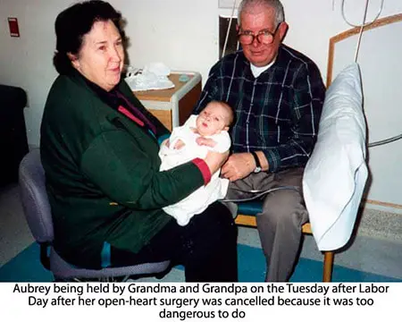 A man and woman holding a baby in a hospital room.