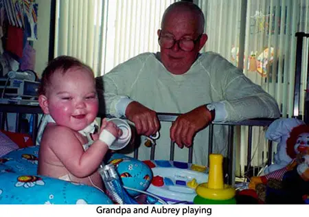 A baby and an older man playing with toys.
