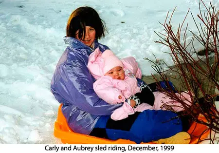 A woman and child sitting in the snow.