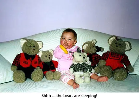 A baby sitting on top of a bed with several stuffed animals.