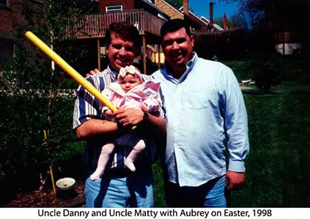A man holding a baby and another man with a bat.