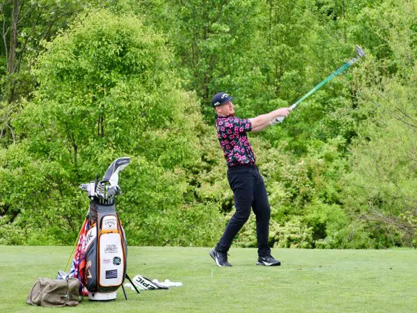 A man swinging at a golf ball on the green.